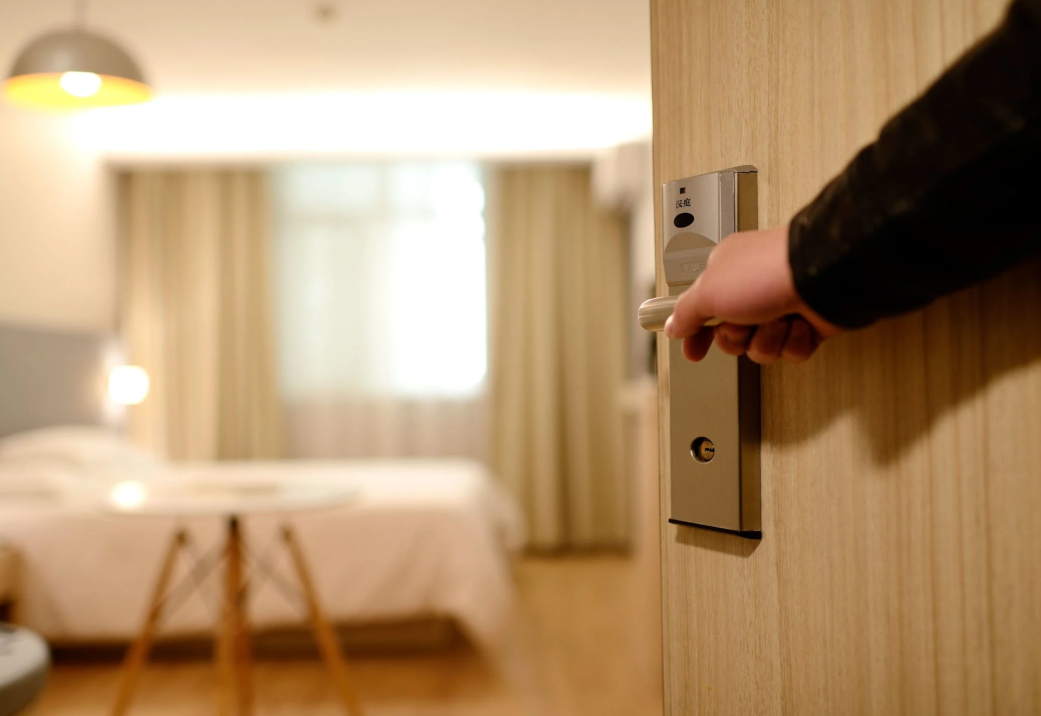 Eine Hand die die Tür zu einem Hotelzimmer öffnet